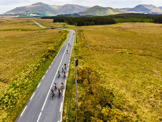 Professional cyclists competing in Connemara region in Ireland. Scenic Irish countryside landscape with mountains on the horizon, County Galway, Ireland.