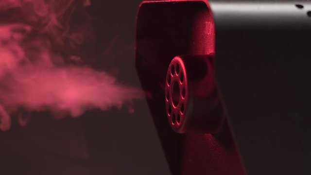 Closeup on a fog smoke machine at work shooting a white smoke.