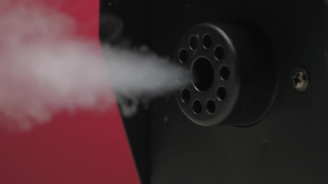 Closeup on a fog smoke machine at work shooting a white smoke.