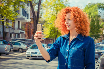 redhead girl making selfie using a smartphone and smiling