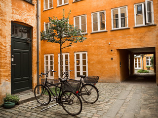 Fototapeta na wymiar Bicicletas en Copenhague contra una fachada amarilla en el verano de 2017.