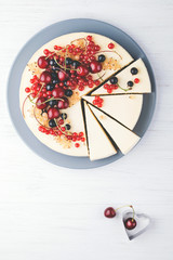 Homemade cheese cake New York with berries on white wooden table. Top view. Red currant, black currant and cherry.
