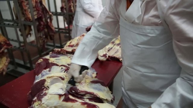 Butchers cutting meat at meat factory