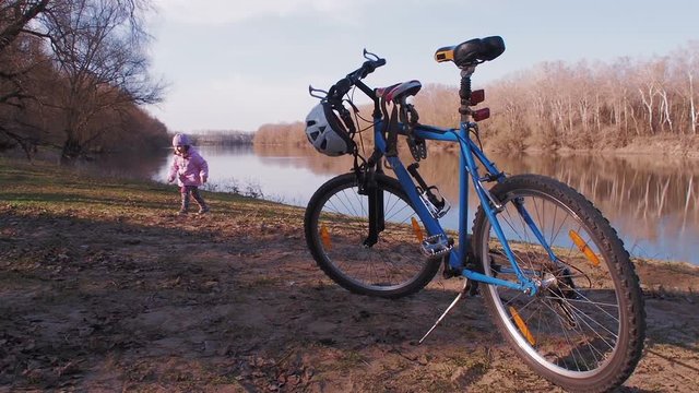 A child is playing by the river. Bicycling in nature.