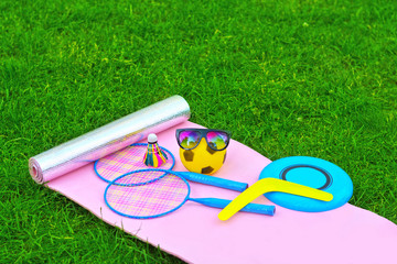 Set for outdoor outdoor games, badminton, rackets, shuttlecock, ball, boomerang, flying disc, sunglasses, on green grass