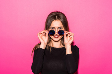 Naklejka premium Trendy young woman portrait with round sunglasses on pink background