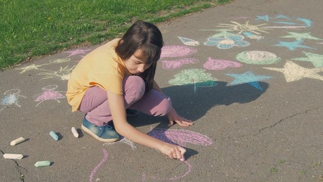 Little artist. A girl is drawing a heart with chalk.