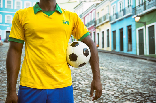Brazilian soccer player standing on colonial Bahia street Pelourinho Salvador with football