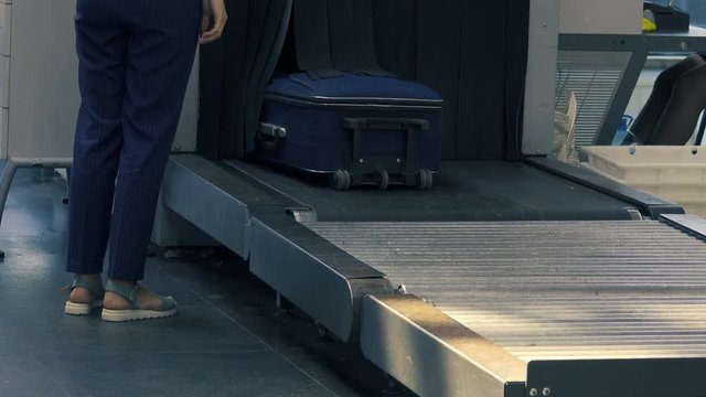 Girl takes her luggage from the luggage tape after checking the safety