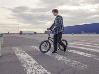 portrait of young man with bmx bicycle walking across the street
