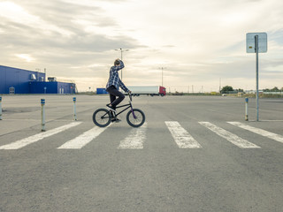 young man riding a bmx bicycle bike crossing the urban street