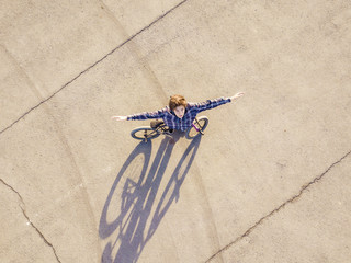 aerial view of young man with raised hands with bicycle standing on sphalt copy space freedom concept