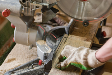 Saw the board. The man saws the board with an electric saw. Joinery.