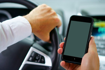 Don't text and drive ! A man is texting with a finger while a car is arriving in front.  focus on the finger, focus on telephone, focus on the car coming.