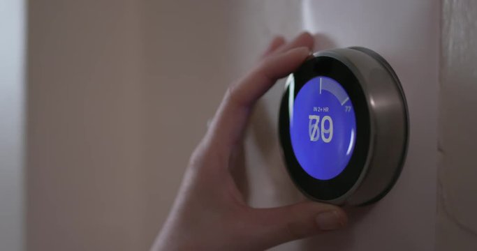 Woman Turning Up Temperature of Smart Thermostat Gadget At Home - Close