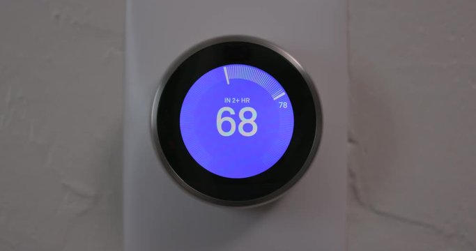Woman Decreasing Temperature of Smart Thermostat Gadget At Home - Close