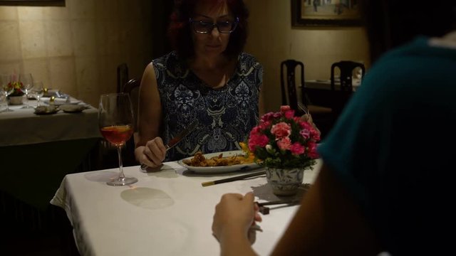 In the restaurant, a woman sitting at a table, eating and talking