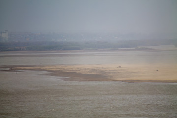 sandstorm in a river valley with green forest on the horizon seen from above