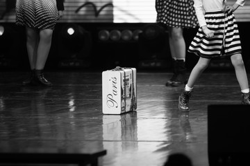 black and white photo of a black and white photo of a suitcase with lower parts of models posing on...