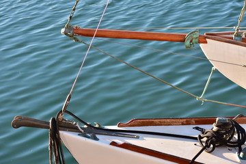 Bows of two classic white wooden sail ships with calm water surface in background.