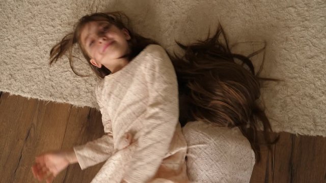 Cute little children sisters girls at home play lie and roll over floor rug smile to camera top view