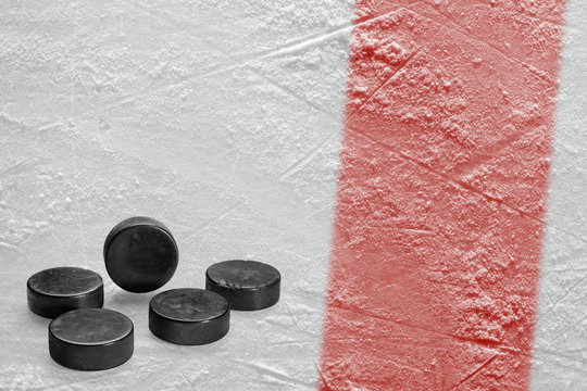 Hockey pucks and a fragment of the ice arena with a red line