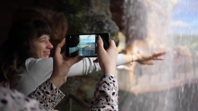 Young females have fun take mobile phone pictures in a zoo waterfall