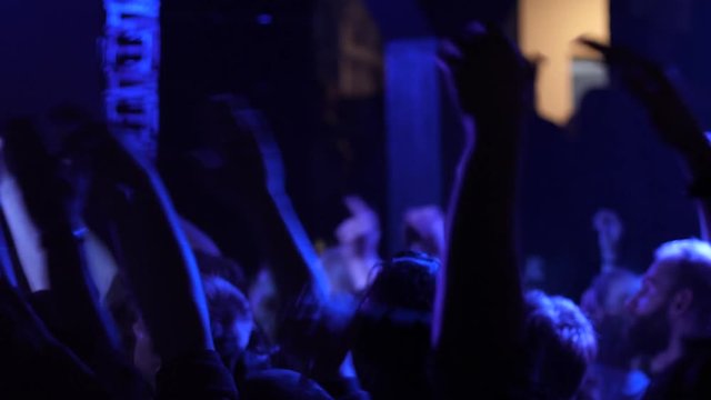 Jubilant cheering crowd of young people dance jump and raise hands on free music concert