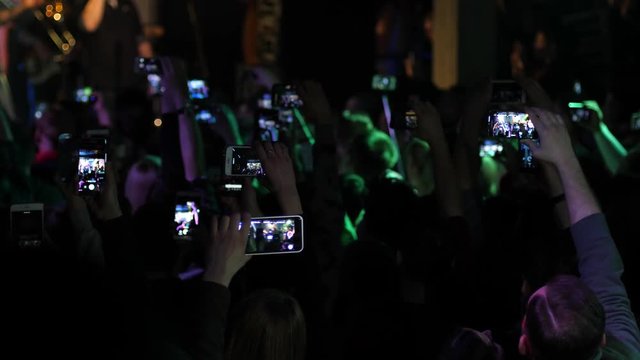 Spectators people crowd raising hands shoot mobile phones video of free music concert