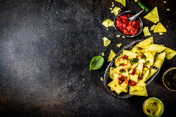 Mexican food, nachos snack with salsa and sauces on dark rusty background top view copy space