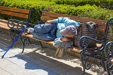 Homeless man is sleeping on a park bench