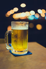 A glass of beer with bokeh light background on the bar.