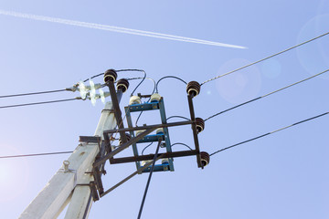 Electricity transmission pole, high voltage equipment, power lines and wires against blue sky.