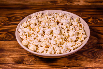Ceramic plate with popcorn on wooden table