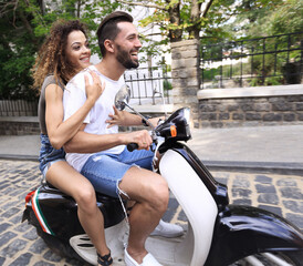 Obraz premium Stylish young couple sits a scooter in the street.