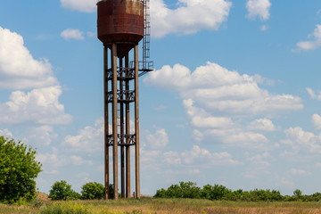 Old rusty water tower in the green field