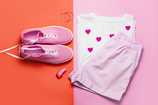 Top view of white woman t-shirt and pink shoes on pink and red background. Fashion clothes and accessories set. Flat lay. Place for text. 90's style