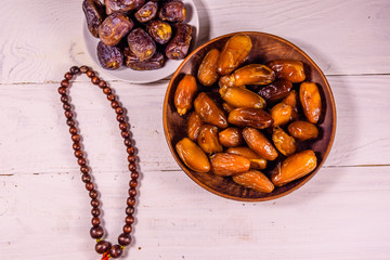 Date fruits and rosary on wooden table. Top view