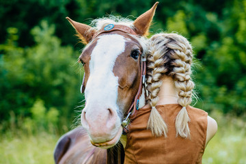 Close up of horse and young blonde woman with two braids hugging. People and animals friendship...