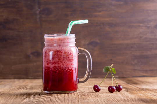 Healthy eating, food, dieting and vegetarian concept - glass smoothies from cherry, closeup, wooden background