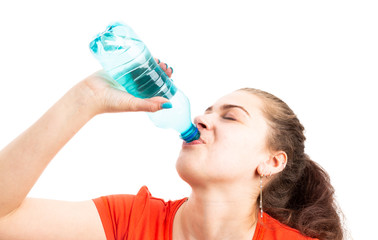 Young woman refreshing by drinking water from plastic bottle.