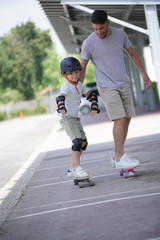 Young boy with dad learning how to skate