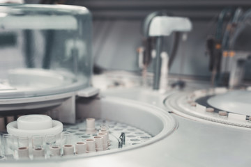 Hospital service. Selective focus of test tubes being put in test holders among laboratory equipment