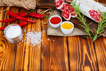 Sliced cured sausage with spices and a sprig of rosemary.