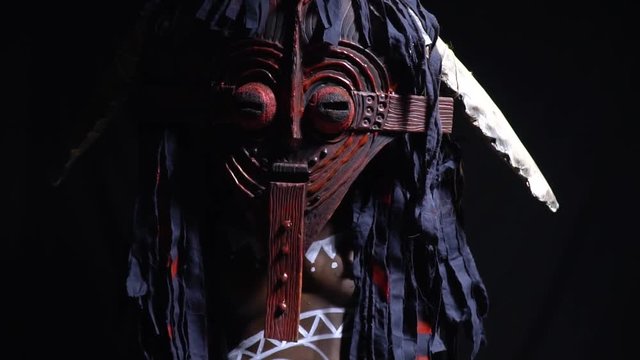 The shaman in a wooden mask slowly turns on the camera