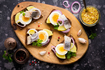 Sandwich on bread with herring, potatoes, egg, onion, tasty appetizer with mustard