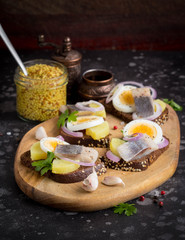 Sandwich on bread with herring, potatoes, egg, onion, tasty appetizer with mustard