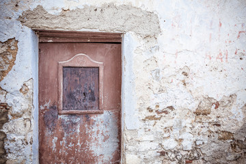 Old brown door and weathered stone wall. Abandoned building