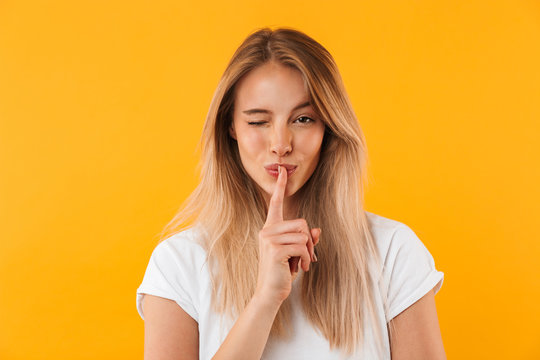 Portrait of a pretty young blonde girl showing silence gesture