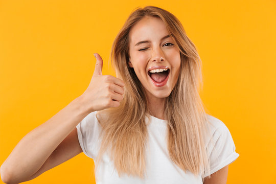 Portrait of a cheerful young blonde girl showing thumbs up